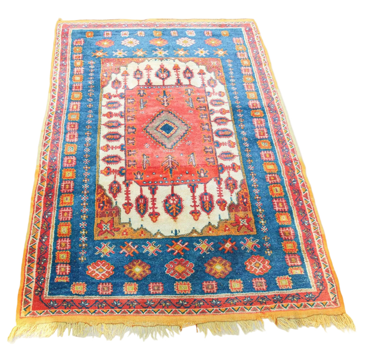A vibrant Moroccan Berber rug featuring geometric patterns in orange, blue, and pink colors, with a fringed edge.