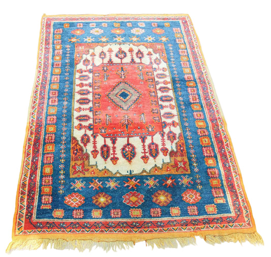 A vibrant Moroccan Berber rug featuring geometric patterns in orange, blue, and pink colors, with a fringed edge.