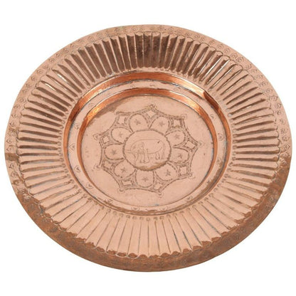 A polished round copper tray with a geometric design in the middle and an elephant in the center, against a light background.