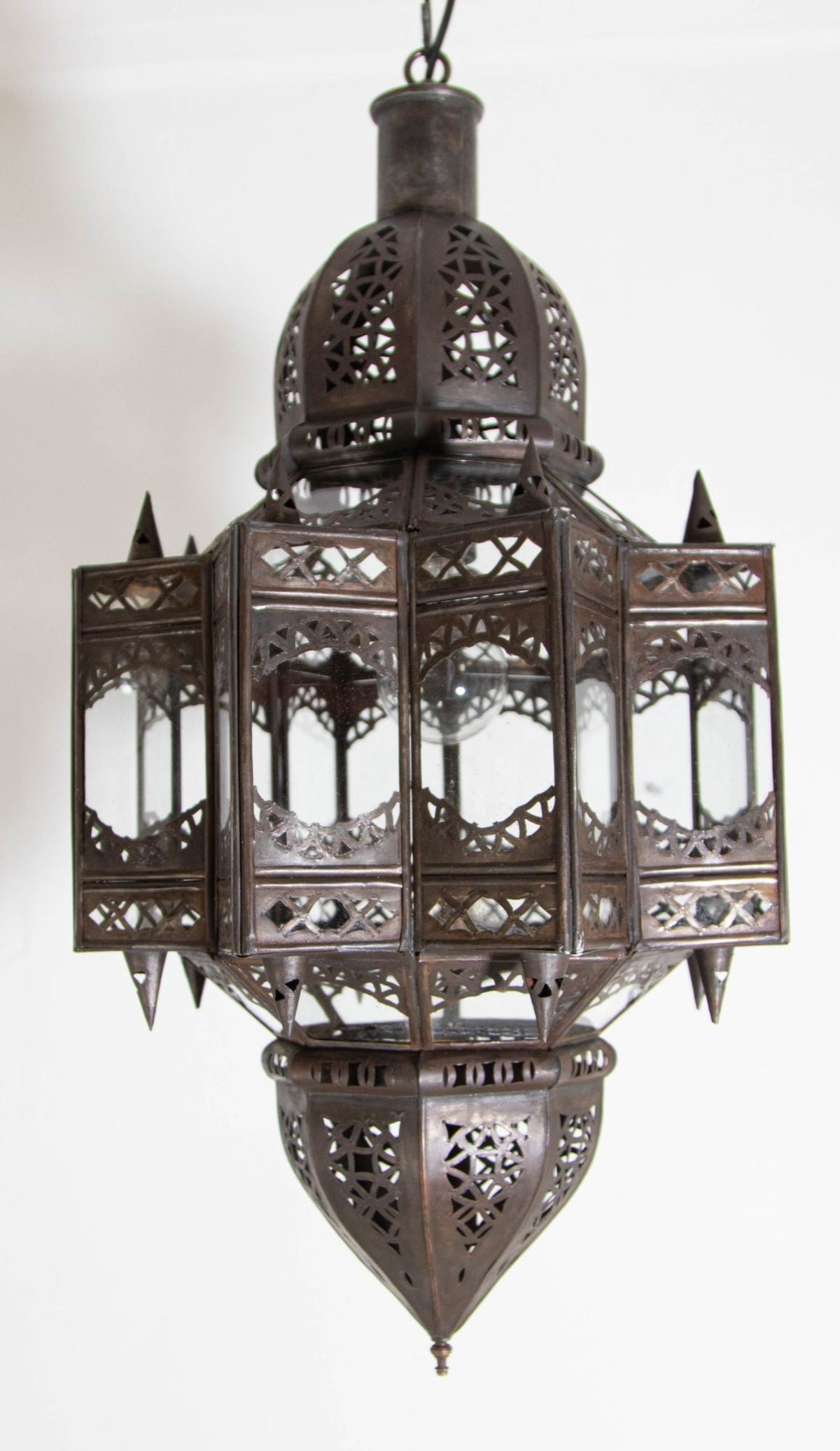 A vintage Moroccan Moorish star-shaped lantern with clear glass and metal, featuring intricate geometric patterns and a dark bronze metal finish. 