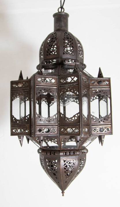 A vintage Moroccan Moorish star-shaped lantern with clear glass and metal, featuring intricate geometric patterns and a dark bronze metal finish. 