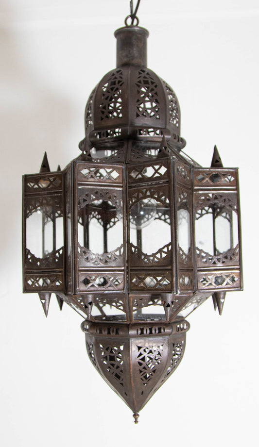 A vintage Moroccan Moorish star-shaped lantern with clear glass and metal, featuring intricate geometric patterns and a dark bronze metal finish.