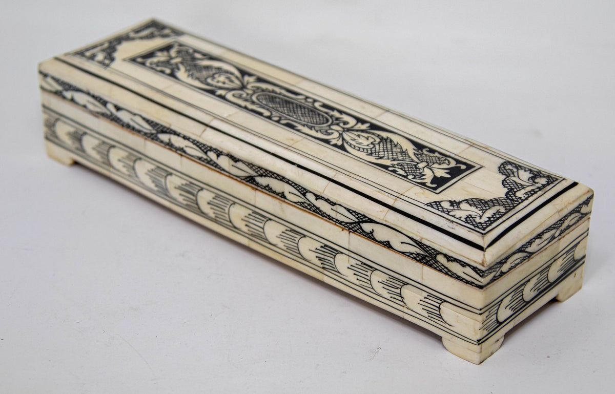 A rectangular, decorative Vizagapatam carved bone jewelry box with black hand-painted patterns and brass hardware.