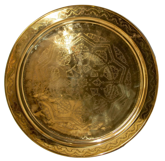 A polished round Moroccan brass tray with intricate geometric patterns.