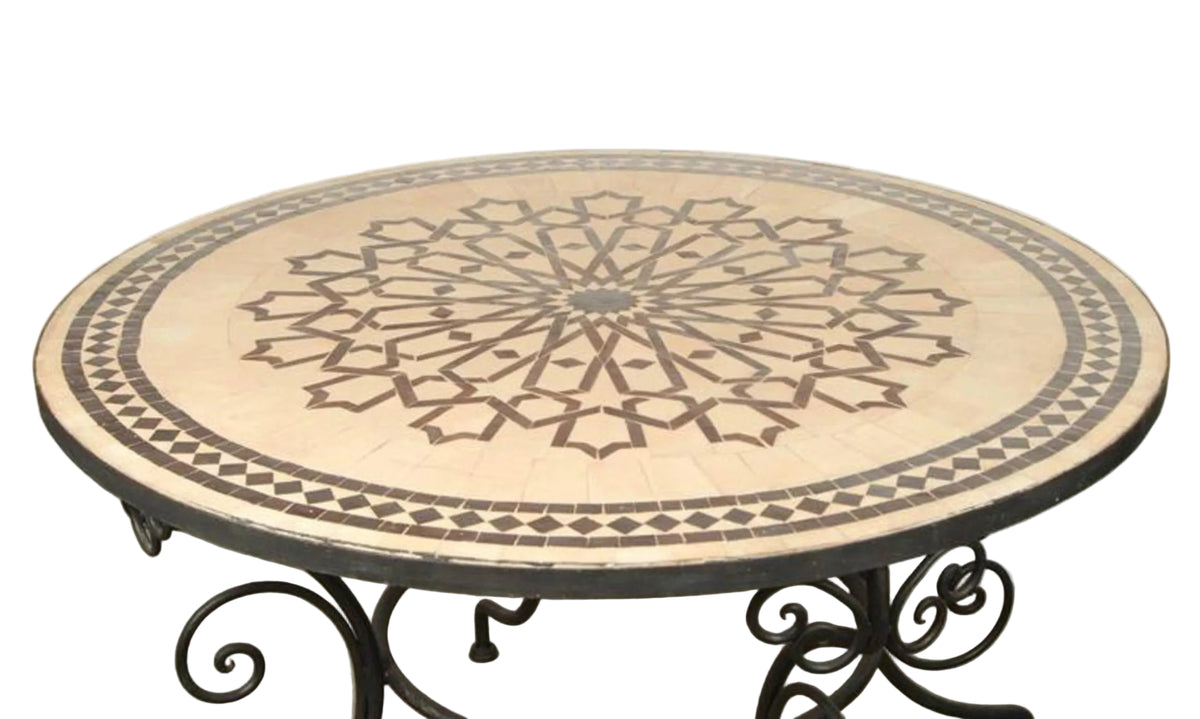 A round Fez Moroccan mosaic tile table with a geometric star design, sitting on a black wrought iron base.