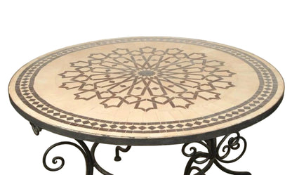 A round Fez Moroccan mosaic tile table with a geometric star design, sitting on a black wrought iron base.