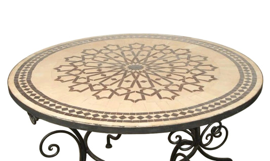A round Fez Moroccan mosaic tile table with a geometric star design, sitting on a black wrought iron base.