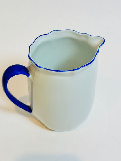 White pitcher with blue rim and handle on a white background