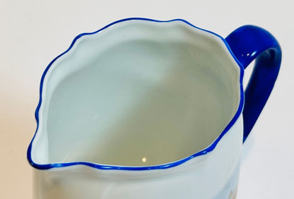 White pitcher with blue rim and handle on a white background