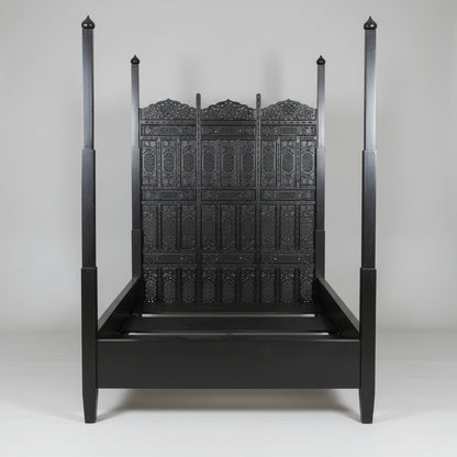 A black four-poster bed with intricate carvings and a Moorish arched head panel, Indo Portuguese Moorish Mughal Raj queen Bed, Anglo Indian hand-carved Bed.