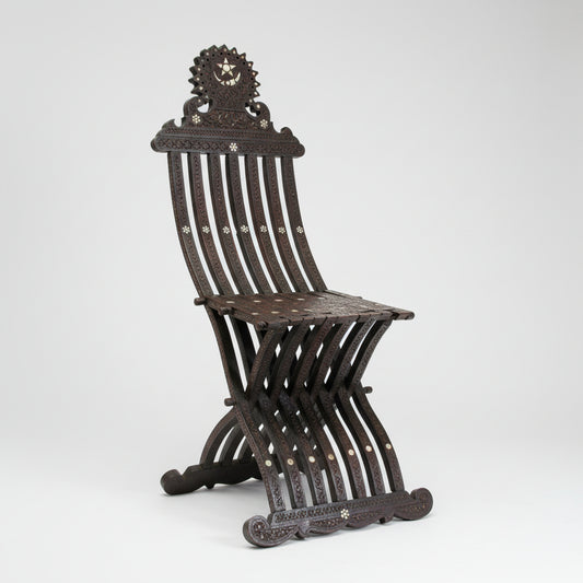 Antique Middle Eastern Moorish walnut wood folding chair with intricate carvings and shell inlays, featuring a seat and backrest with visible Arabic calligraphy. 