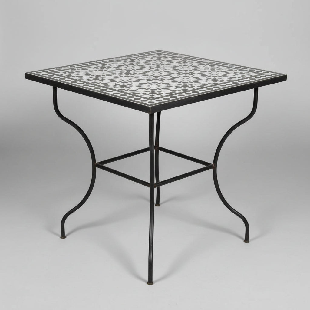 A Moroccan square table with a black and white geometric mosaic tile top and a black metal frame, 