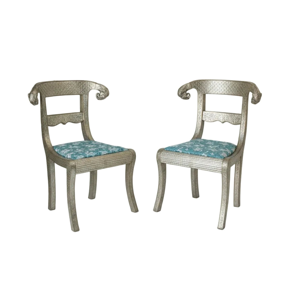 A pair of Anglo-Indian silvered wrapped clad side chairs with upholstered seats in blue and carved wooden legs, featuring intricate metalwork and elephant head designs. 