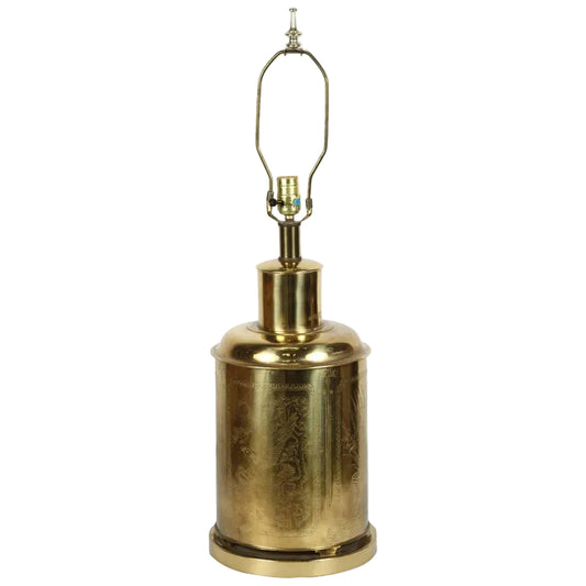 A polished handcrafted brass tea canister with a floral and birds design, converted into a table lamp with a harp on top.